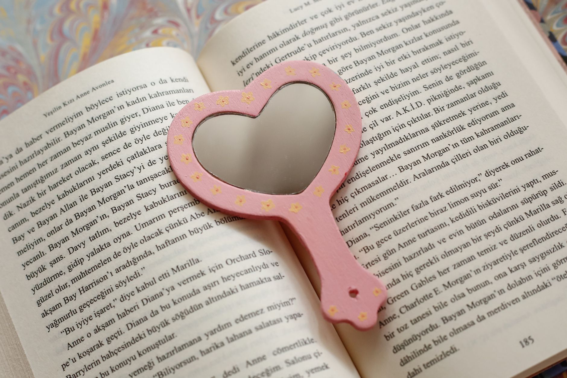 Heart-shaped mirror resting on an open book